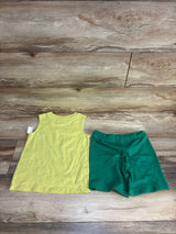 Sleeveless yellow kids shirt and green shorts set on wood background, children's clothing