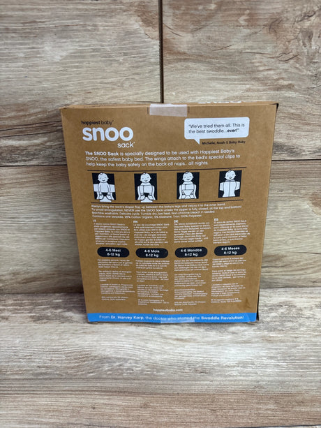 Back view of Happiest Baby SNOO sleep sack packaging showcasing safe-use diagrams and 4 to 6 month sizing on a wood surface