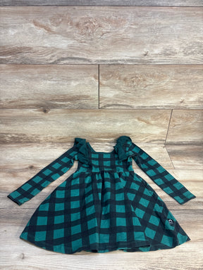 Green and black plaid long sleeve girls dress with ruffle shoulders on wooden floor