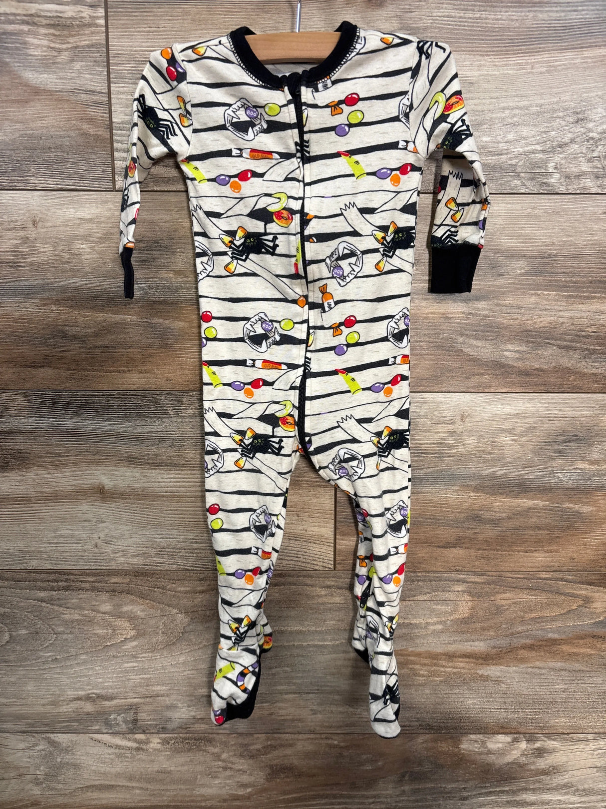 Halloween-themed baby footed pajamas with candy and spider prints on striped background
