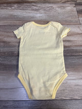 Yellow striped baby bodysuit by Me n Mommy To Be laid flat on a wooden surface.