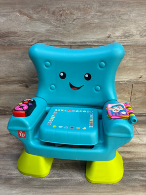 Front view of Fisher-Price Laugh & Learn Smart Stages chair in teal showing smiling face backrest, interactive buttons on armrests and alphabet seat against wood background