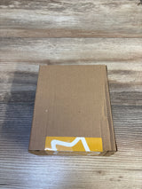 Top view of Tommee Tippee 4-pack breast-like soothers in sealed brown shipping box with yellow sticker on wood tabletop