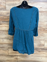Front view of blue maternity lace top showing ladder lace trim, empire waist and three-quarter sleeves on a black mannequin against wood background
