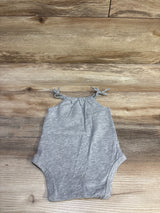 Flat lay of Okie Dokie grey 3M baby bodysuit showcasing knotted shoulder straps and heathered fabric on wood background