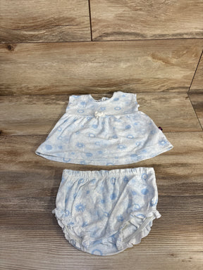 Flat lay of newborn white two-piece floral shirt and bloomer set showing pale blue flower print and bow on wood backdrop