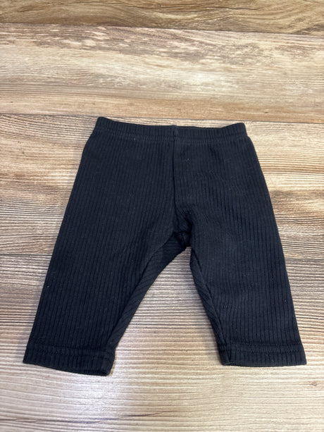 Front view of Carter’s black ribbed leggings in size 3 months showing elastic waistband and vertical ribbing on wood