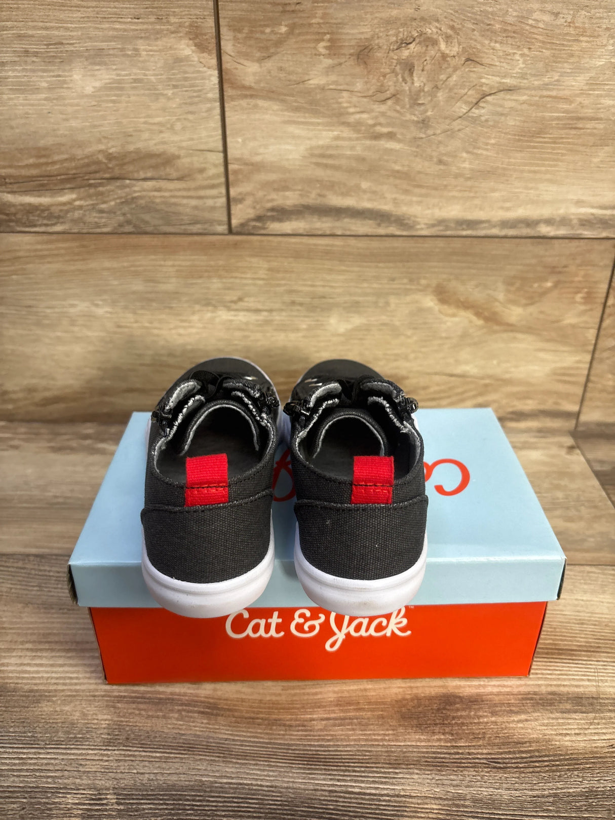 Rear view of Cat & Jack Lucian toddler grey double-zipper sneakers showing red heel tabs and white soles on a Cat & Jack shoebox with wood plank background
