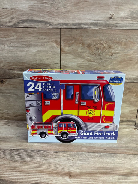 Front view of Melissa & Doug 24 piece giant fire truck floor puzzle box showcasing fire truck artwork on a wood surface