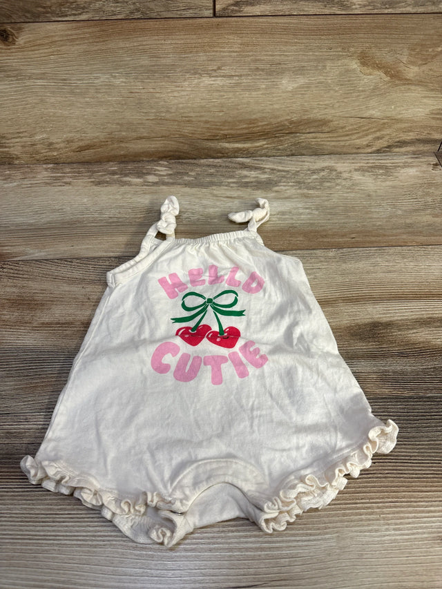 Flat lay of ivory Old Navy romper with pink Hello Cutie text and cherry graphic, knotted shoulder straps and ruffled legs on wood