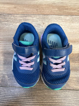 Navy blue toddler sneakers with purple laces and Velcro straps on wood floor