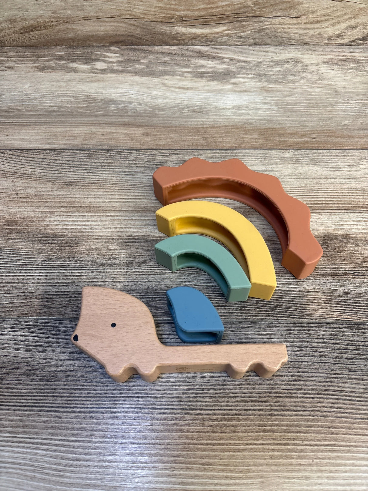 Overhead view of Cloud Island hedgehog stacker showing wooden base and four silicone arches in warm earth tones on wood surface