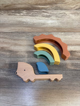 Overhead view of Cloud Island hedgehog stacker showing wooden base and four silicone arches in warm earth tones on wood surface