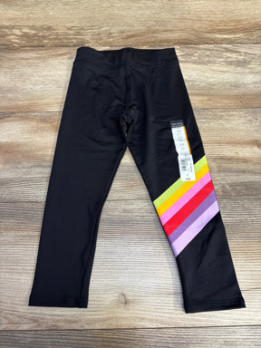 Black toddler leggings with colorful rainbow stripes on right leg, laid on wood surface