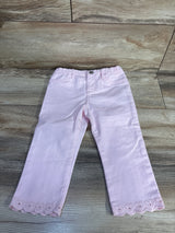Front flat lay of pale pink OshKosh jeans with scalloped embroidered hem, elastic waistband, faux button on wood floor