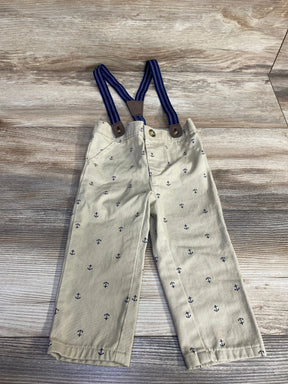 Front view of tan suspender pants, size 12 months, showing navy anchor print and blue striped suspenders on wood background