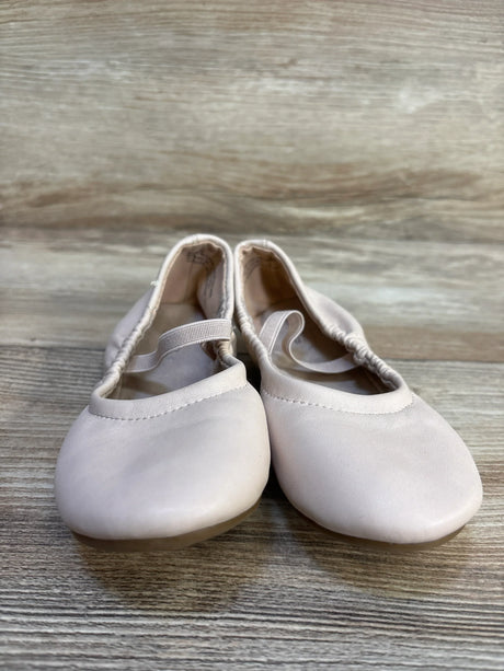 Light pink toddler ballet shoes with elastic straps on wood floor