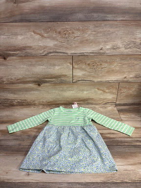 Baby dress with green striped long sleeves and a blue floral skirt on wooden floor