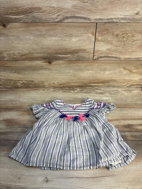 Striped baby dress with pink and navy tassel accents on wood background, gently used