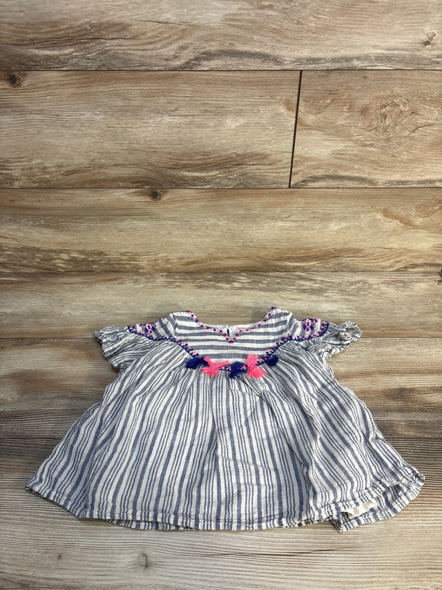 Striped baby dress with pink and navy tassel accents on wood background, gently used