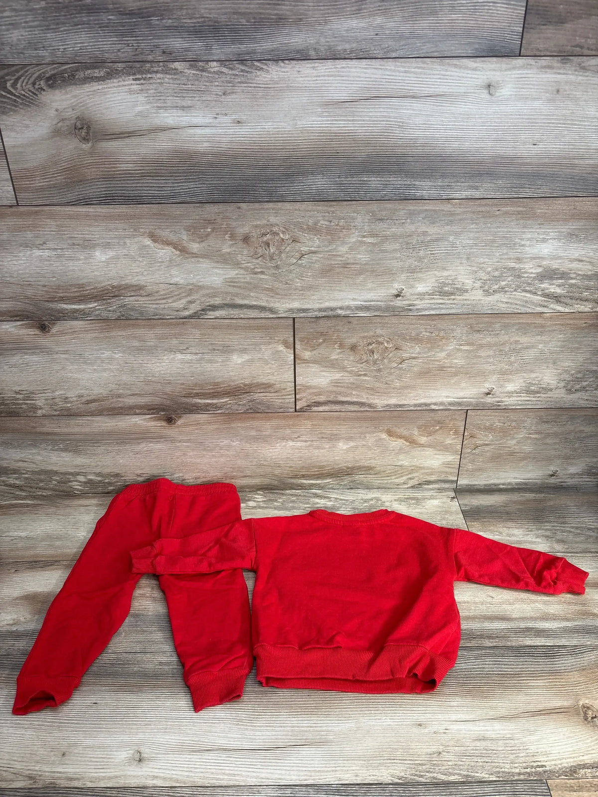 Red baby sweatshirt and pants set on wood floor, kids clothing resale