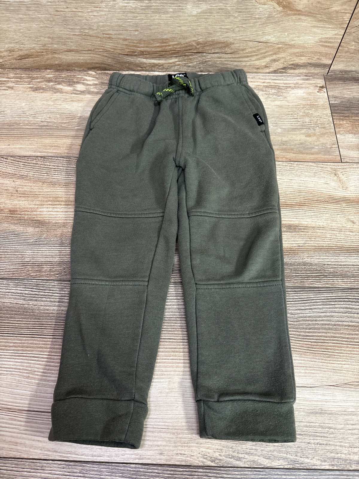 Front view of Lee green drawstring joggers in size 3T showcasing side pockets and paneled legs on a wood-patterned background