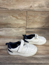 Side view of Carter's Every Step Port sneakers showing white perforated upper, navy heel, and Velcro strap on wood backdrop