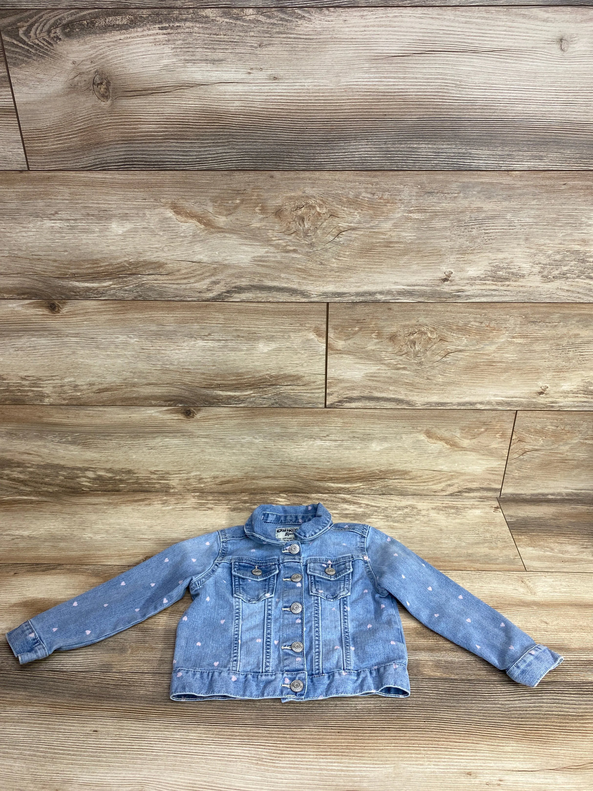 Kids denim jacket with pink heart prints laid flat on wooden floor for children's resale