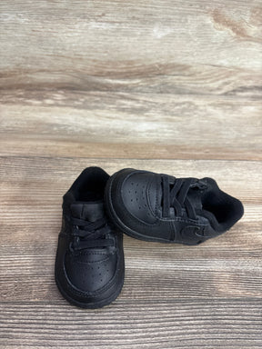Front angle view of black Nike Air Force 1 crib shoes size 4C showcasing perforated toe, laces and Nike Swoosh with wood floor background