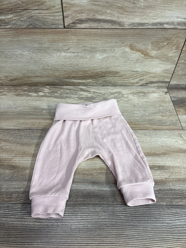 Flat lay of pink H&M foldover-waist baby pants showing fold-over waistband and cuffed legs on wood background