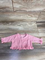 Pink baby cardigan with pearl button and ruffle trim on wooden floor background