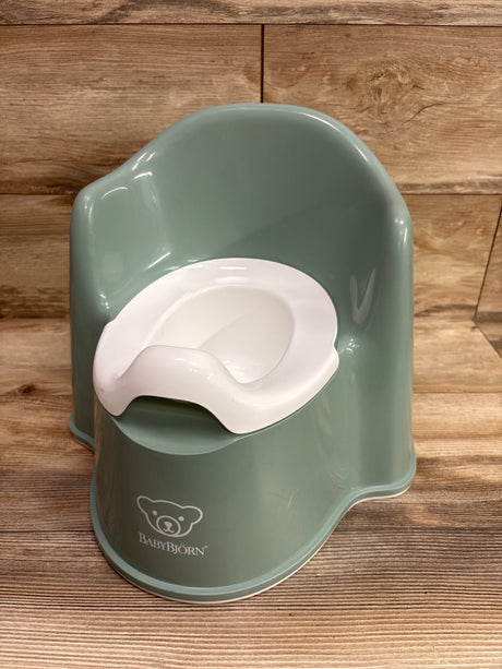 Front view of BabyBjorn Potty Chair in green showcasing its white inner seat with a wood background