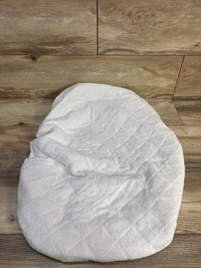 White quilted baby mattress pad on wood floor background