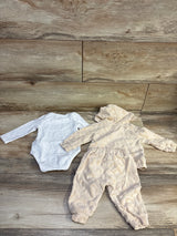 Top-down view of Guess Baby beige three-piece set with hooded patterned zip-up jacket, joggers, and white bodysuit on a wood floor
