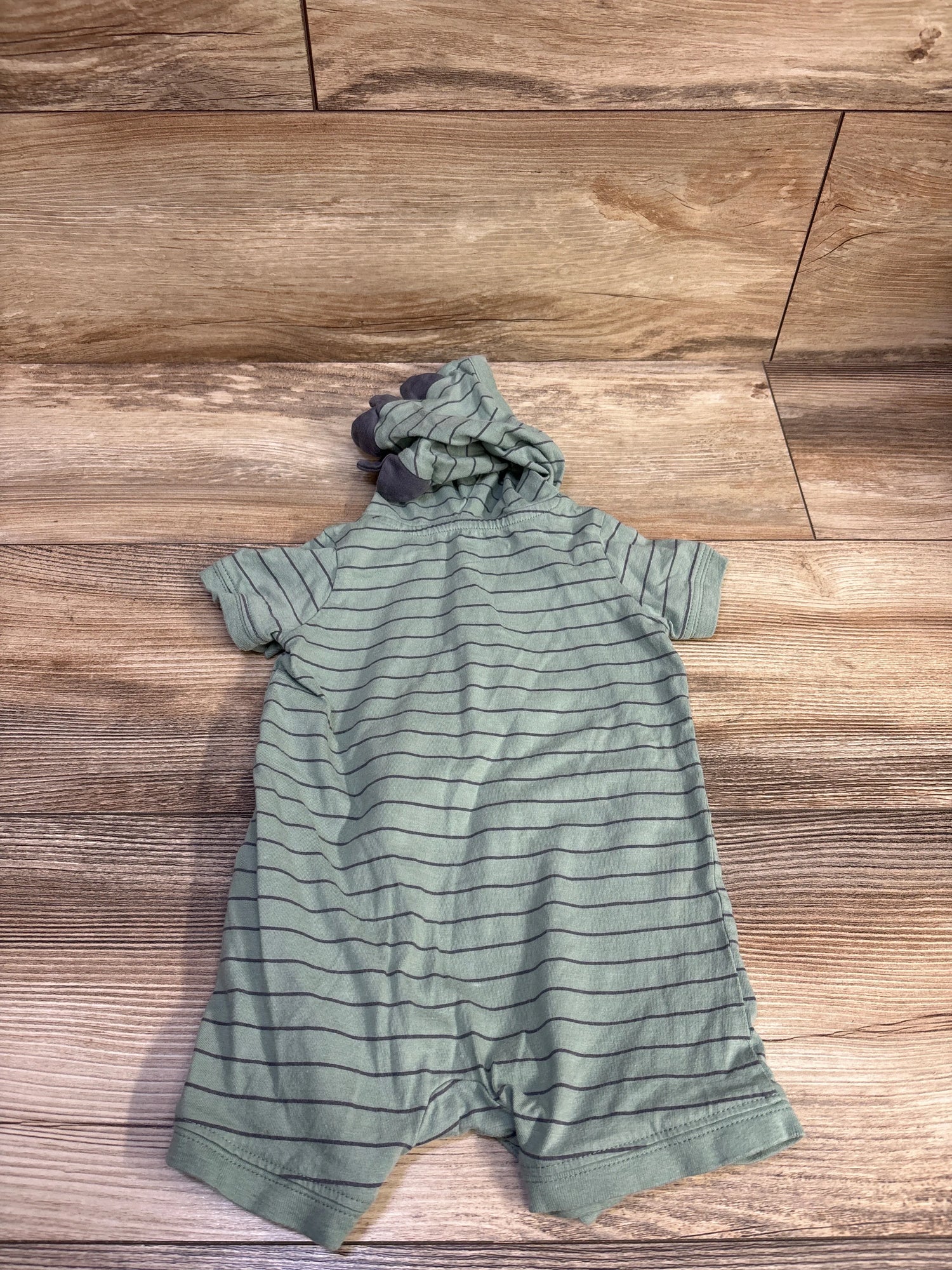 Top view of Carter’s green hooded henley shortie romper showcasing horizontal dark stripes on a wood floor