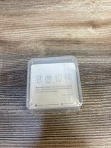 Top view of Moonkie baby finger toothbrushes 2-pack sealed in clear case showing safety icons and warning label on wood surface