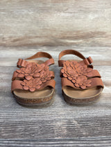 Brown toddler sandals with floral design on cork soles, kids footwear on wood background