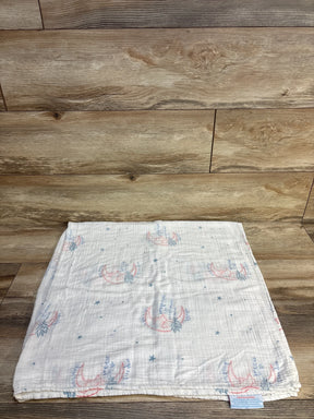 Folded muslin baby blanket with pink moon and blue feather print on wood background