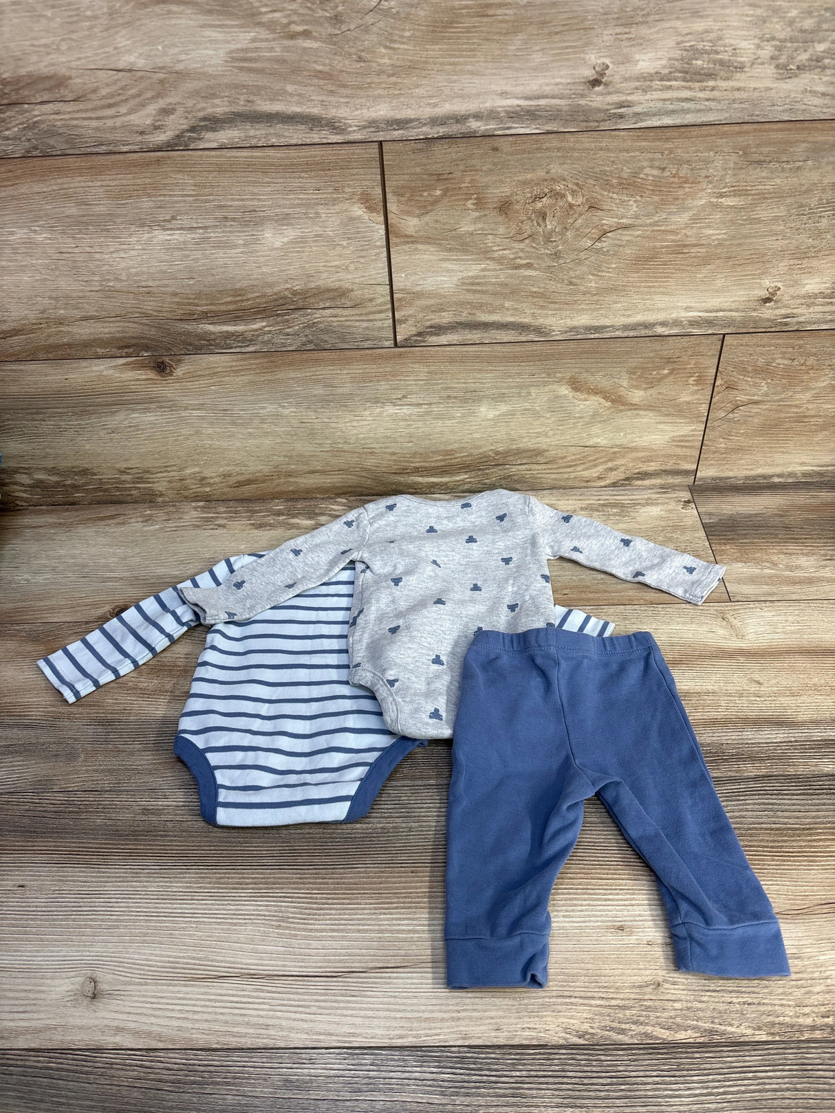 Flat lay of Baby Gap 3-piece infant set: gray bodysuit with small navy whales, navy-striped bodysuit, and blue pants