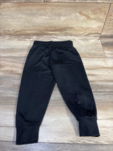 Flat-lay of black Nike toddler joggers size 2T showcasing elastic waistband and ribbed ankle cuffs on light wood floor background