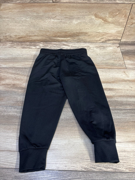 Flat-lay of black Nike toddler joggers size 2T showcasing elastic waistband and ribbed ankle cuffs on light wood floor background