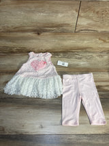 Pink and white lace baby dress with heart detail and matching pink leggings on wood background