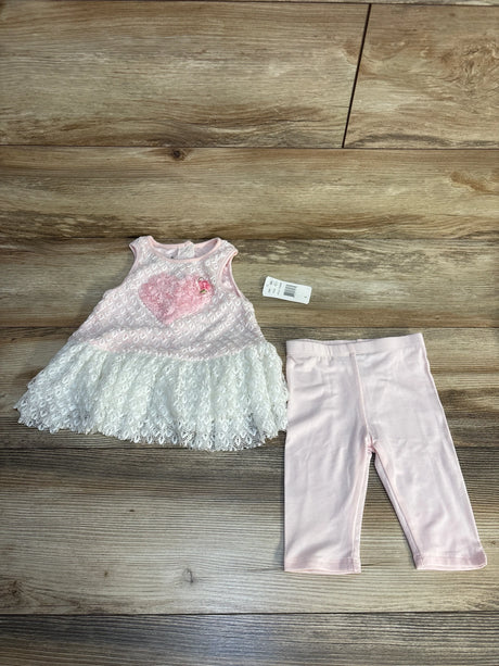 Pink and white lace baby dress with heart detail and matching pink leggings on wood background