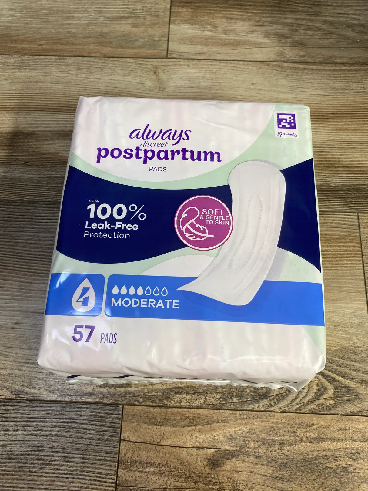 Front view of Always Discreet postpartum pads, moderate absorbency, 57 count, 100 percent leak-free on wood floor