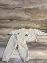Front view of Baby Gap 2-piece pullover sweatshirt and pants set showcasing beige fabric and Gap bear logo on wood flooring