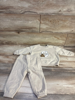 Front view of Baby Gap 2-piece pullover sweatshirt and pants set showcasing beige fabric and Gap bear logo on wood flooring