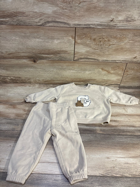 Front view of Baby Gap 2-piece pullover sweatshirt and pants set showcasing beige fabric and Gap bear logo on wood flooring