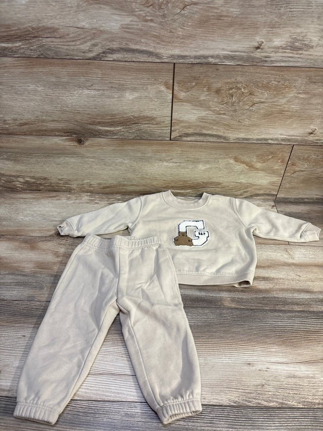 Front view of Baby Gap 2-piece pullover sweatshirt and pants set showcasing beige fabric and Gap bear logo on wood flooring