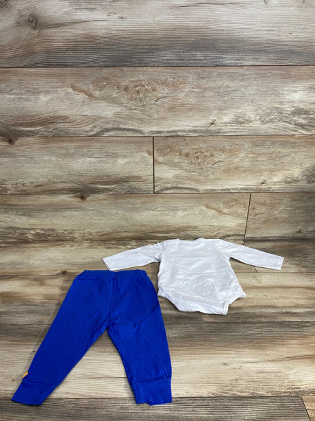 Children's blue pants and white long-sleeve bodysuit laid on wood floor background