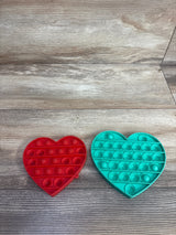 Red and teal heart-shaped silicone pop-it fidget toys on wooden floor